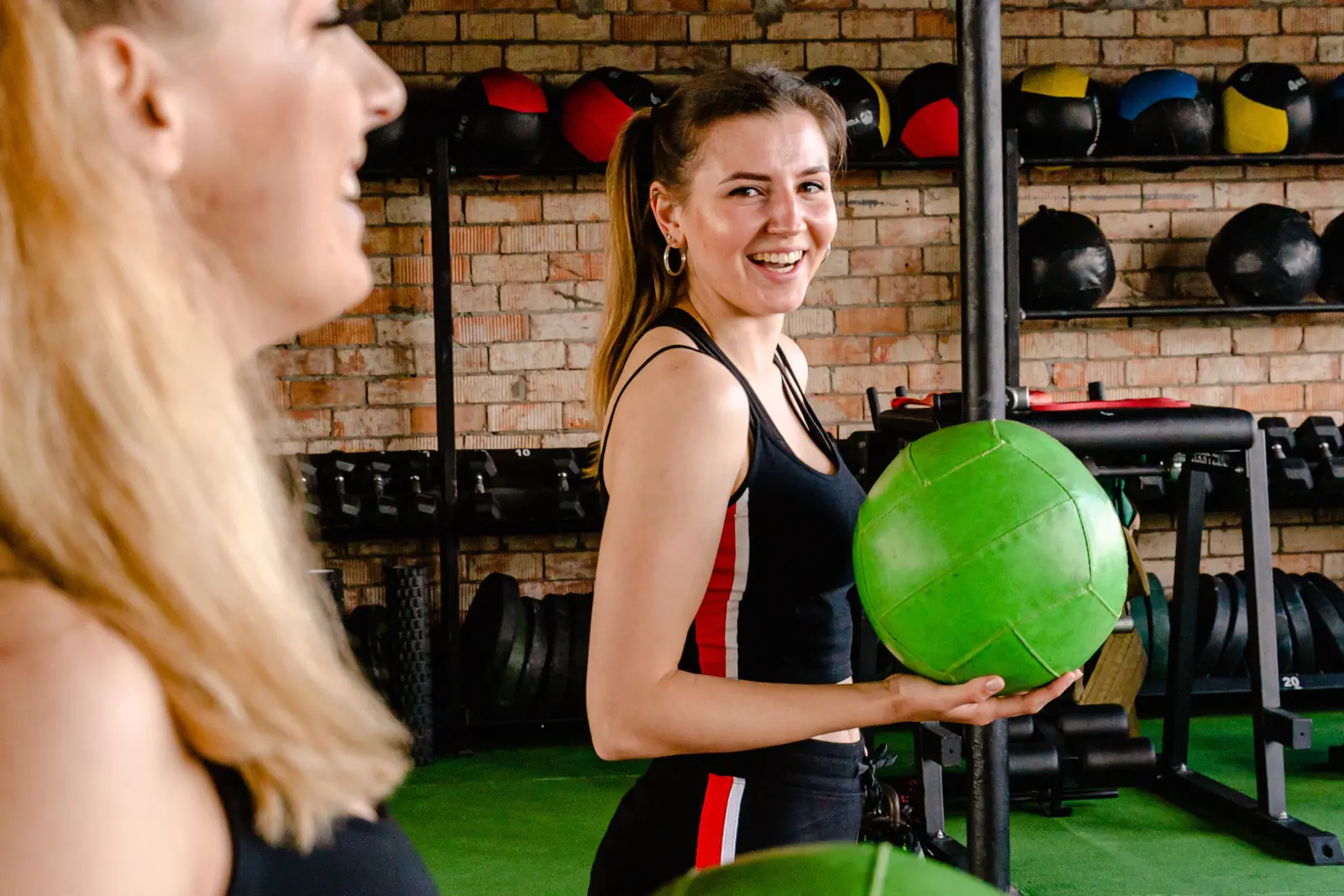 Two friends laughing between sets, medicine balls in hand.